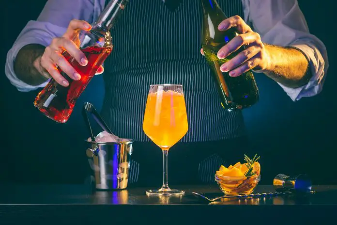 Bartender pouring liquor into a cocktail glass