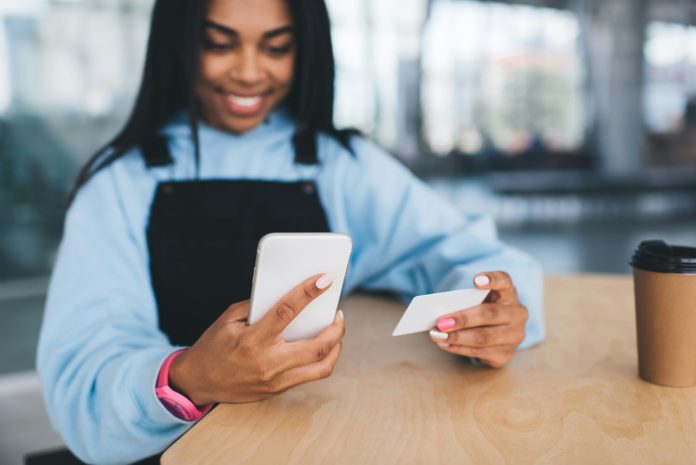 Black girl with business card using mobile phone