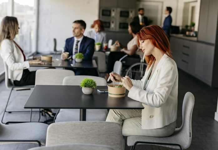 Businesswoman eating salad in modern office cafeteria