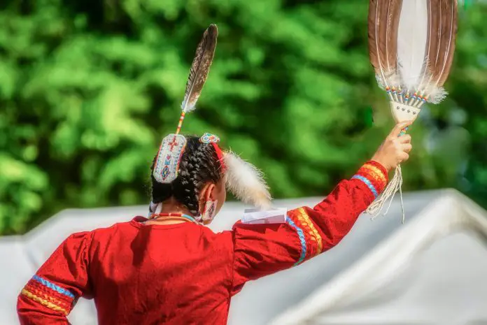 Closeup shot of the head of a person in a traditional Indian-American festive hat with feathers