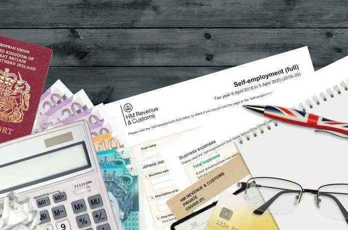 English Tax form sa103 Self-employment from HM revenue and customs lies on table with office items