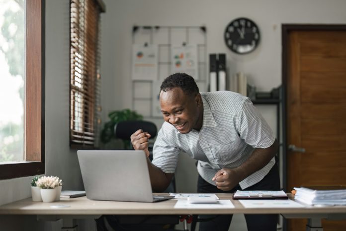 Happy surprised African American businessman reading good news in letter, celebrating success