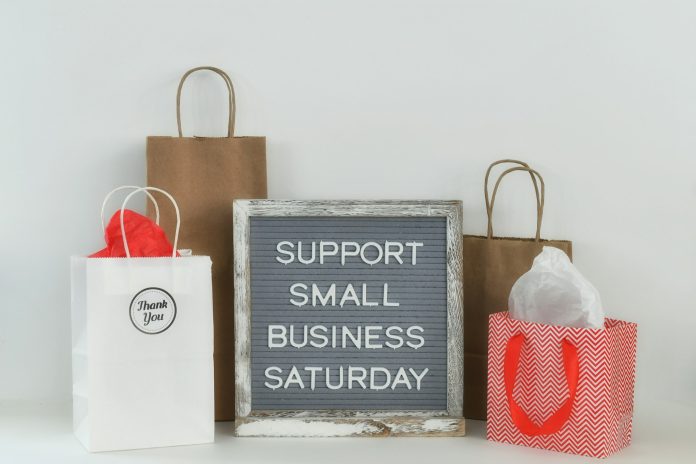 Shopping bags, gift bags, with message board sign saying SUPPORT SMALL BUSINESS SATURDAY, copy space