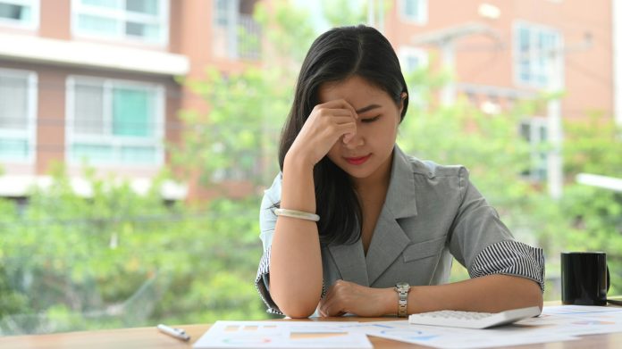 Stressed businesswoman reading document, solving business problem.