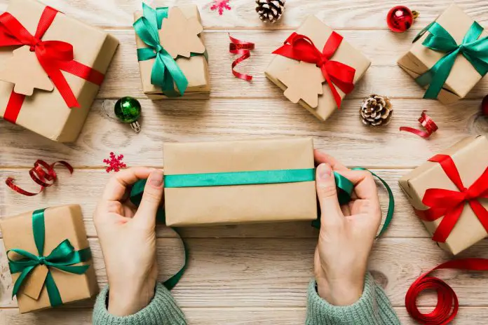 Woman is packing surprise gift for Christmas holidays, sitting at workplace