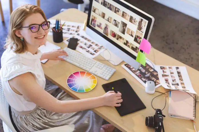 Young Caucasian female graphic designer working on graphic tablet at desk in office.