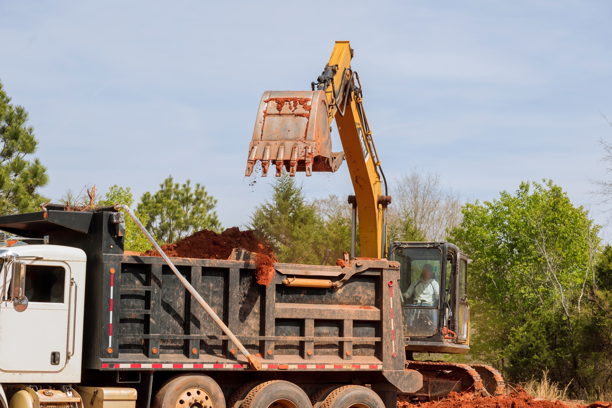 An excavator is loading earth into dump truck on construction site