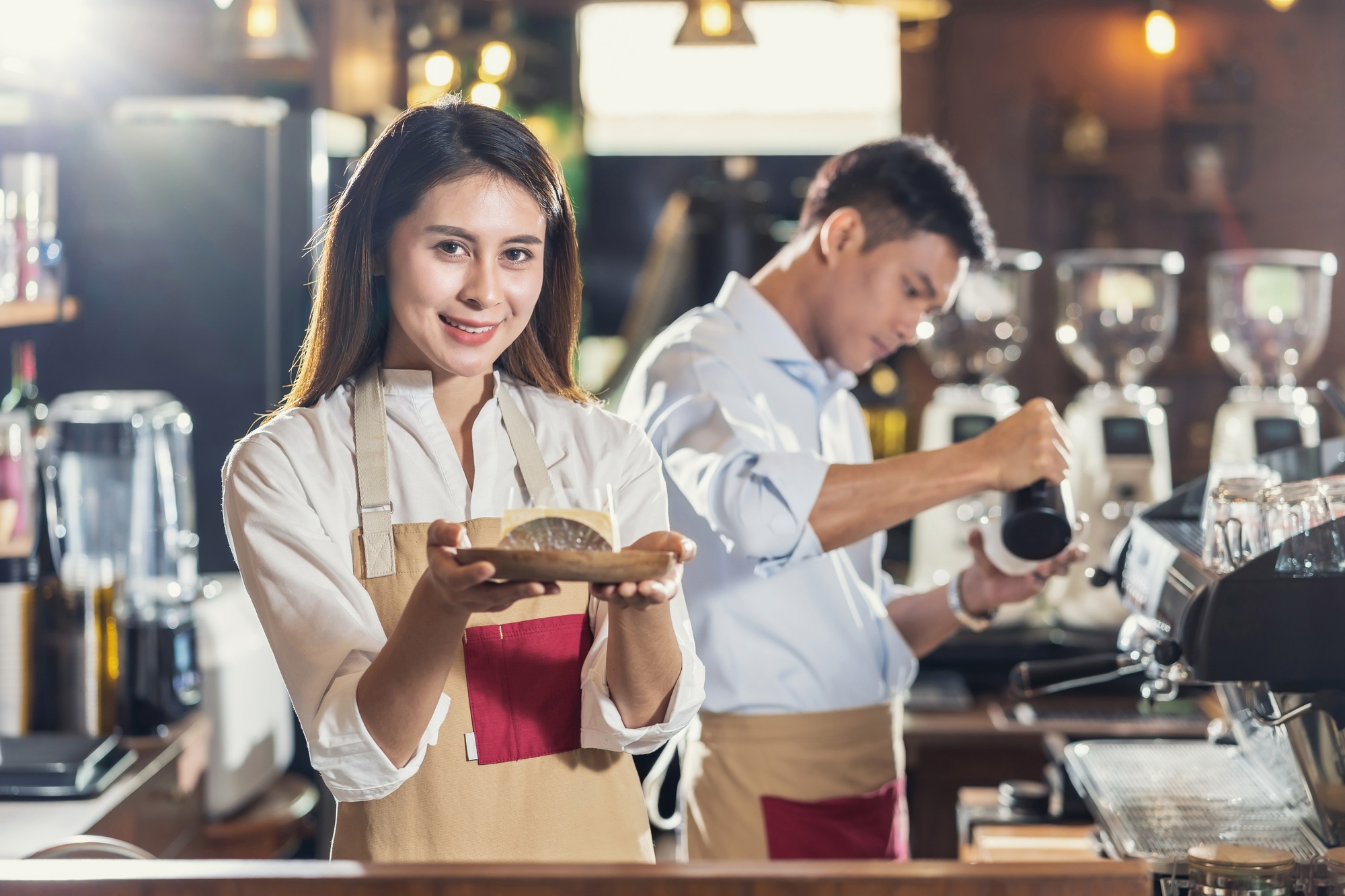 Asian Barista serving bakery cake, preparing cup of coffee, espresso with latte or cappuccino