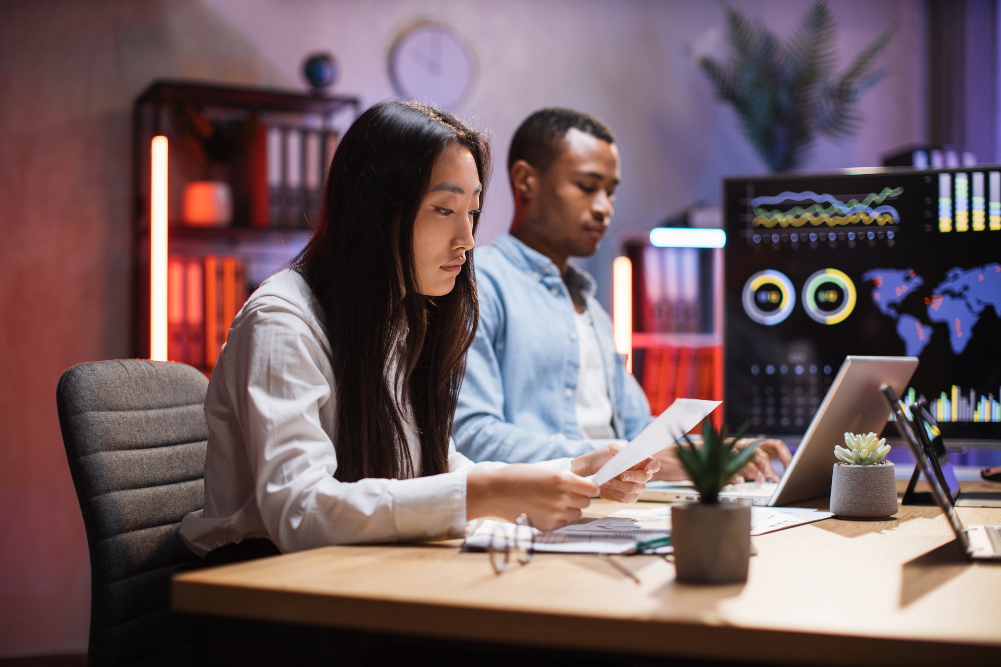 Diverse workers with gadgets analyzing charts at office