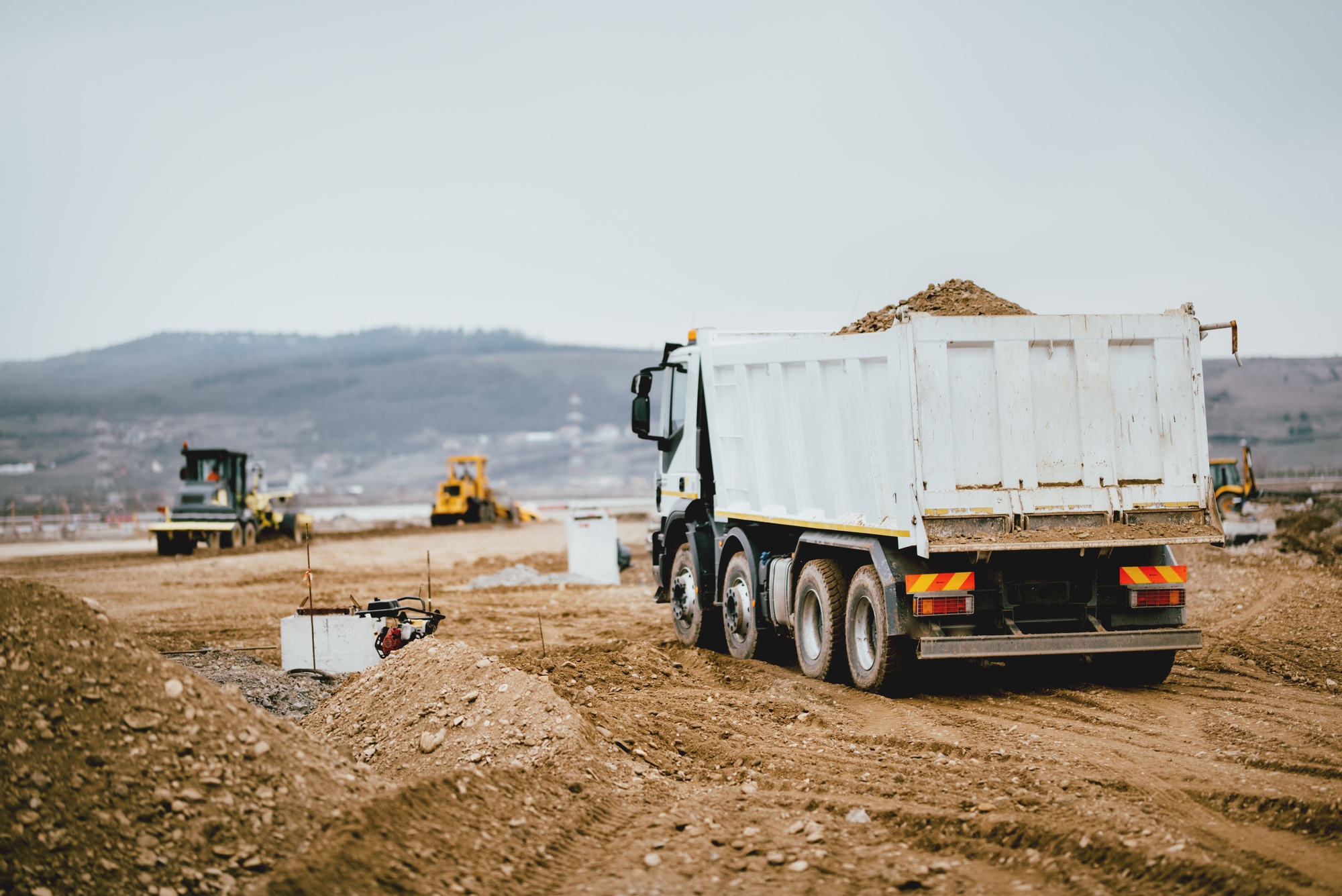 Industrial dumper trucks working on highway construction site,