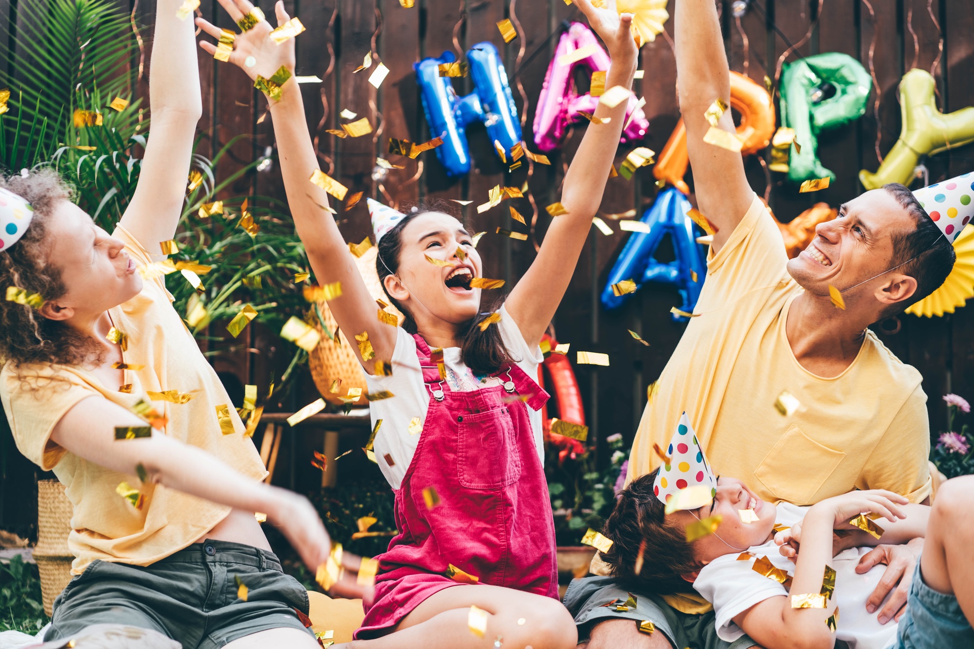 Joyful family with children throws air balloons and golden confetti