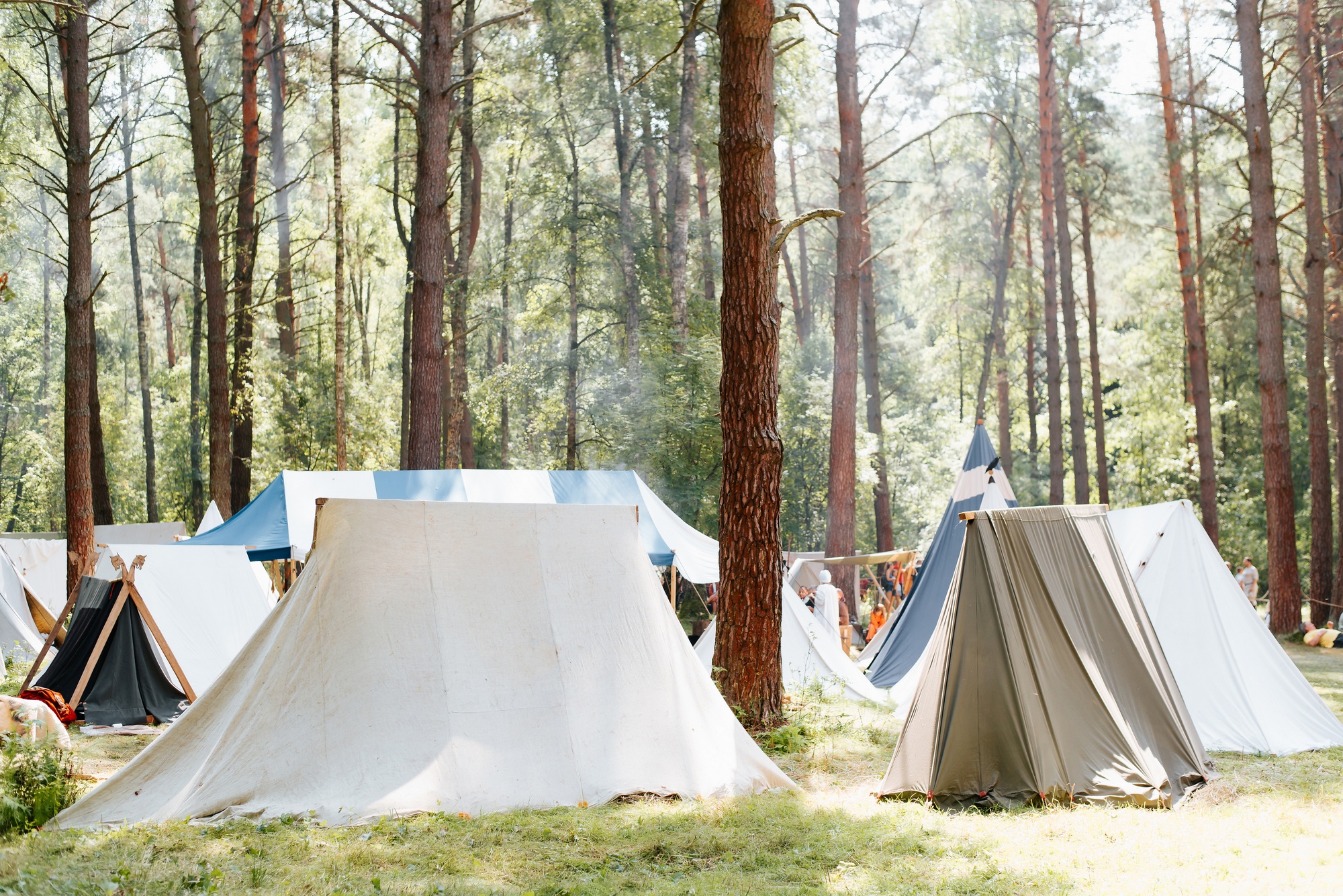 Medieval campground in forest, fabric tents on sunny summer day outdoors. Folk camping lifestyle