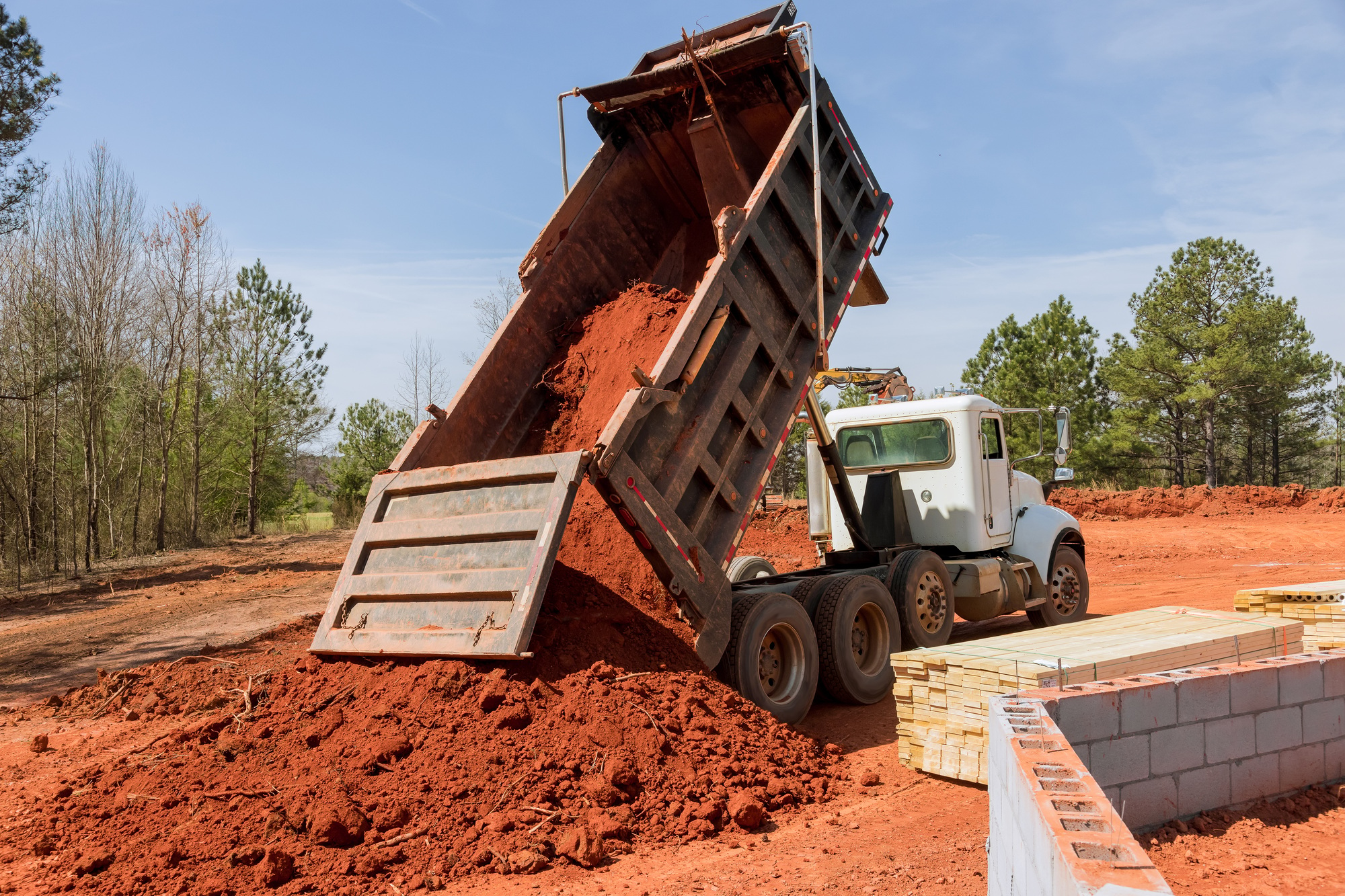 On a construction site, a dump truck is used to move soil down to level the ground