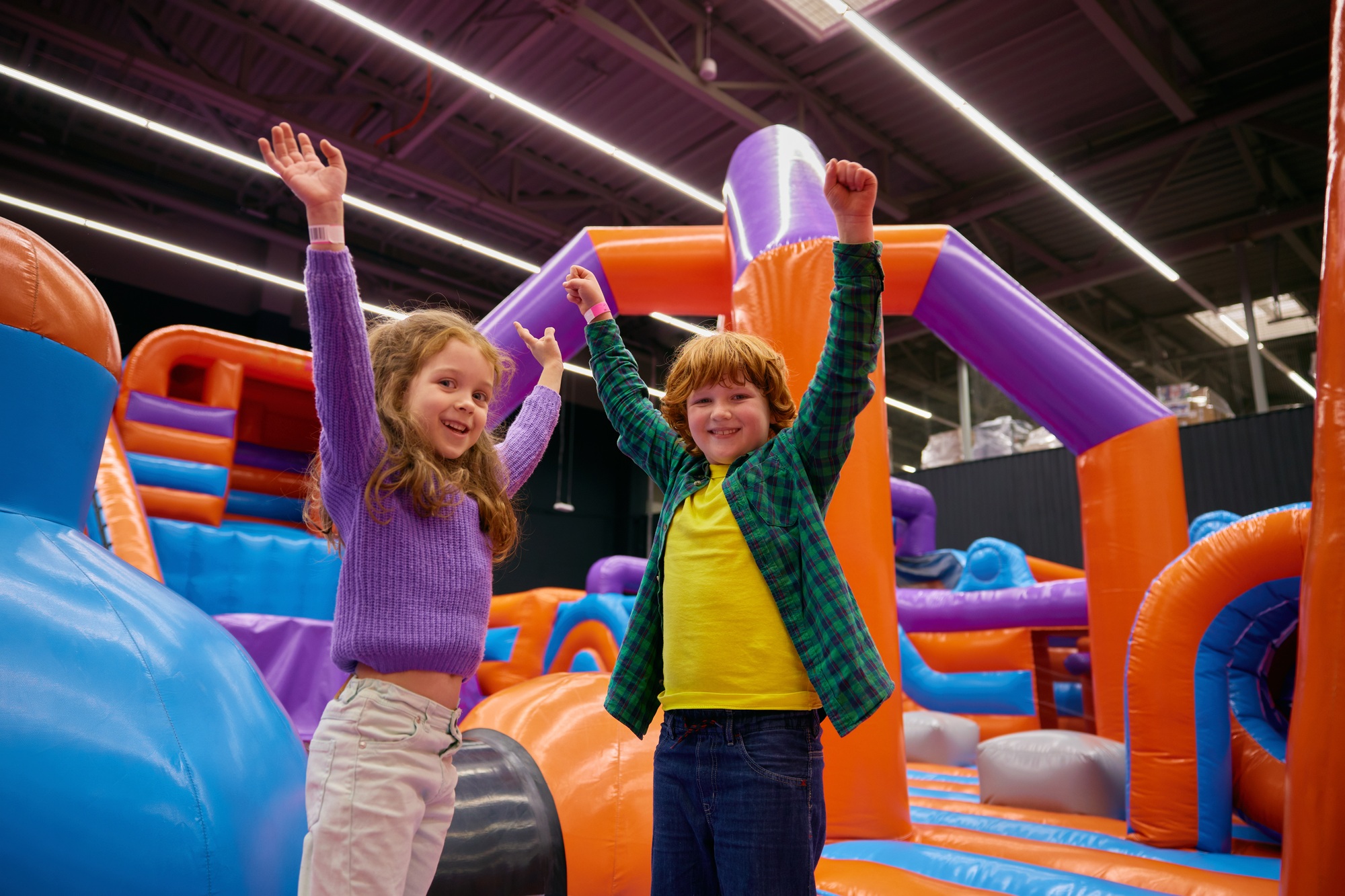 Portrait of happy children with raised hands up playing in bounce house