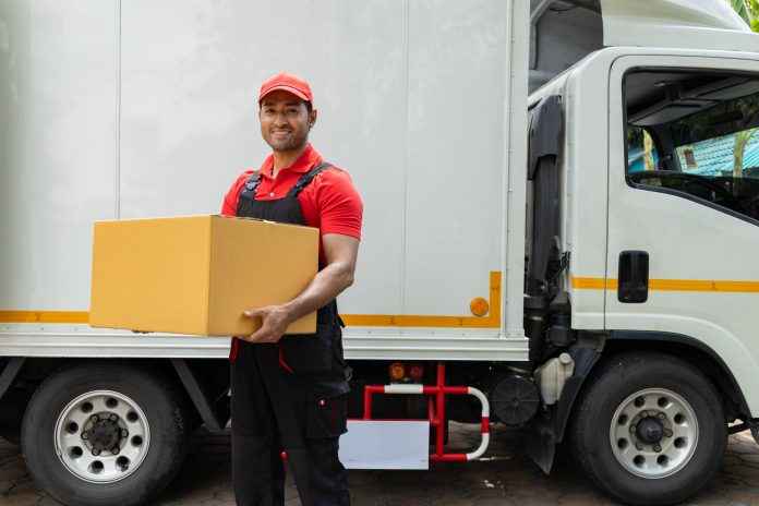 Portrait of two movers unloading boxes and furniture from a pickup truck.