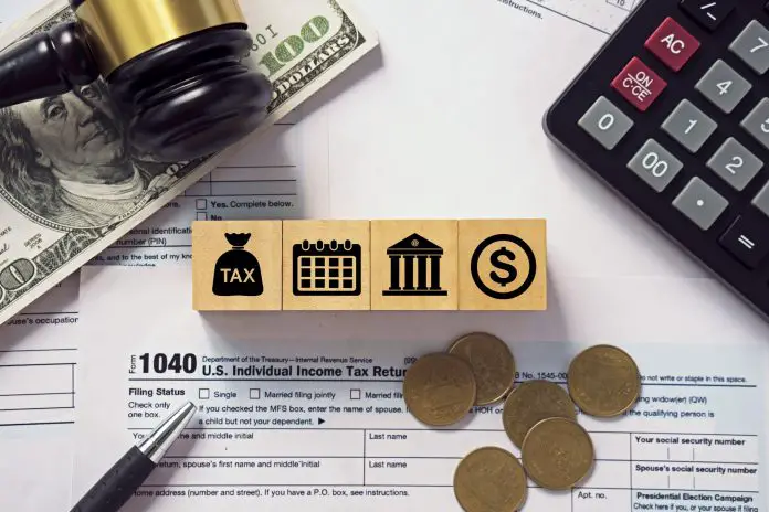 Tax concept.Tax icon on wooden block.Calculator with money on 1040 tax form.Income tax return.