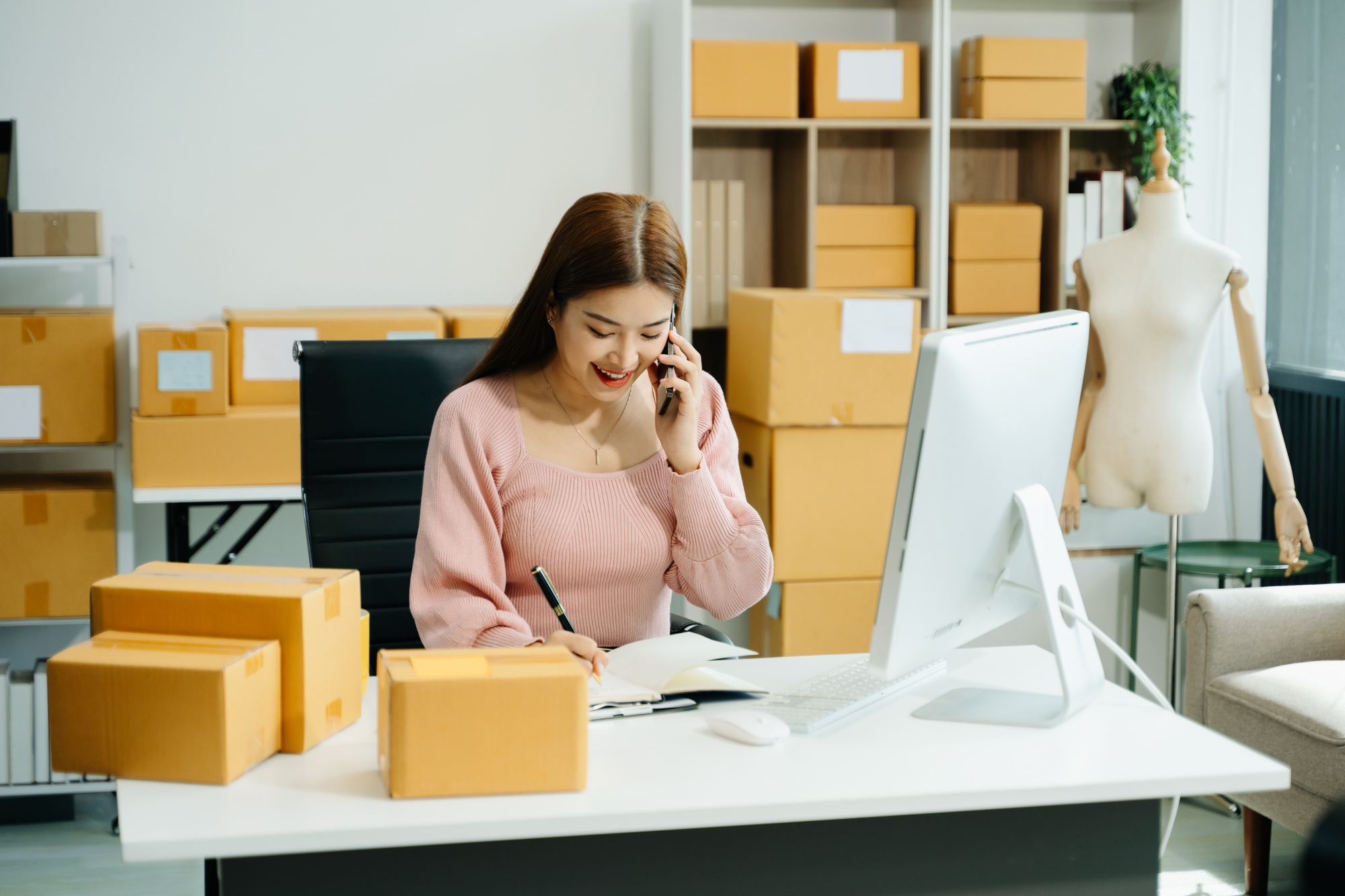 Young businesswoman managing online sales and shipping from a modern home office.