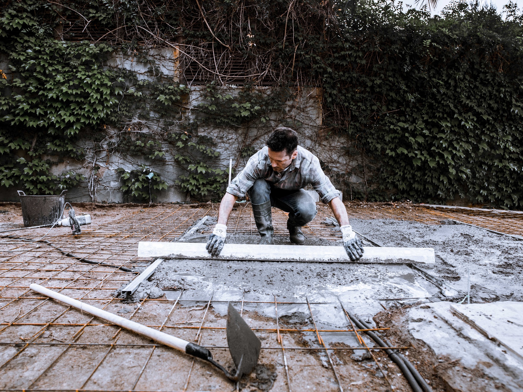 A worker scatters the cement with a shovel.