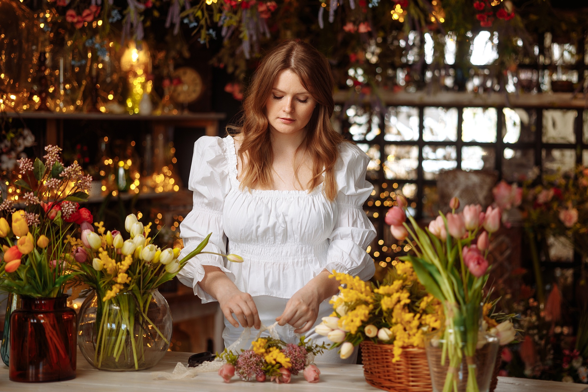 A young florist takes care of flowers in a cozy flower shop