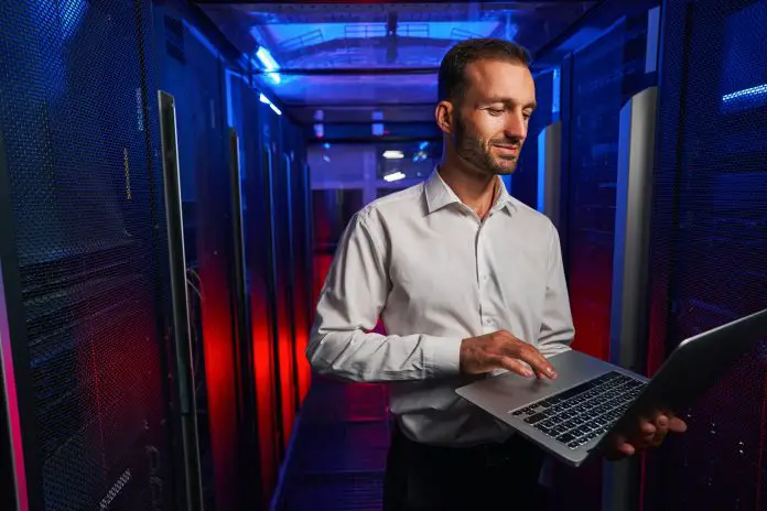 Bearded confident maintenance engineer in white shirt is working in database center