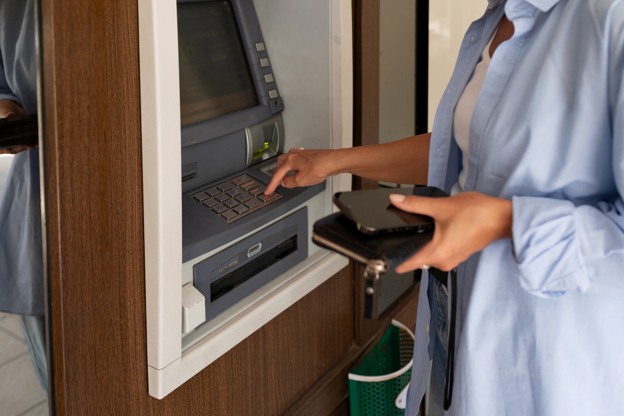 close-up of a woman using an ATM and holding a wallet