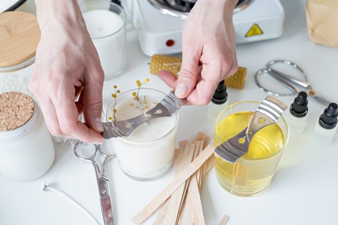 closeup of woman setting the wooden wick into handmade candle