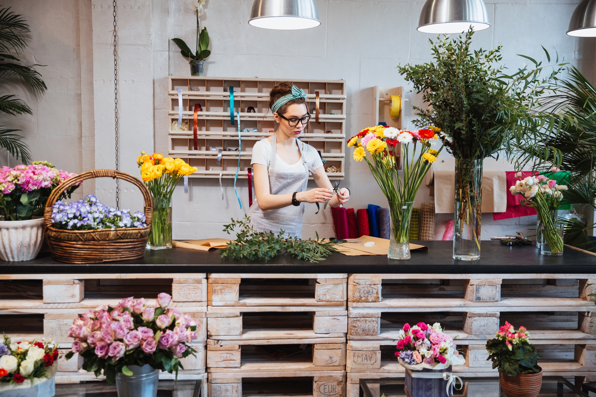 Cute concentrated female florist working in flower shop