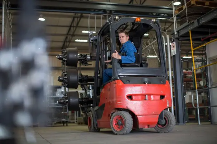 Factory working driving a fork lift in warehouse