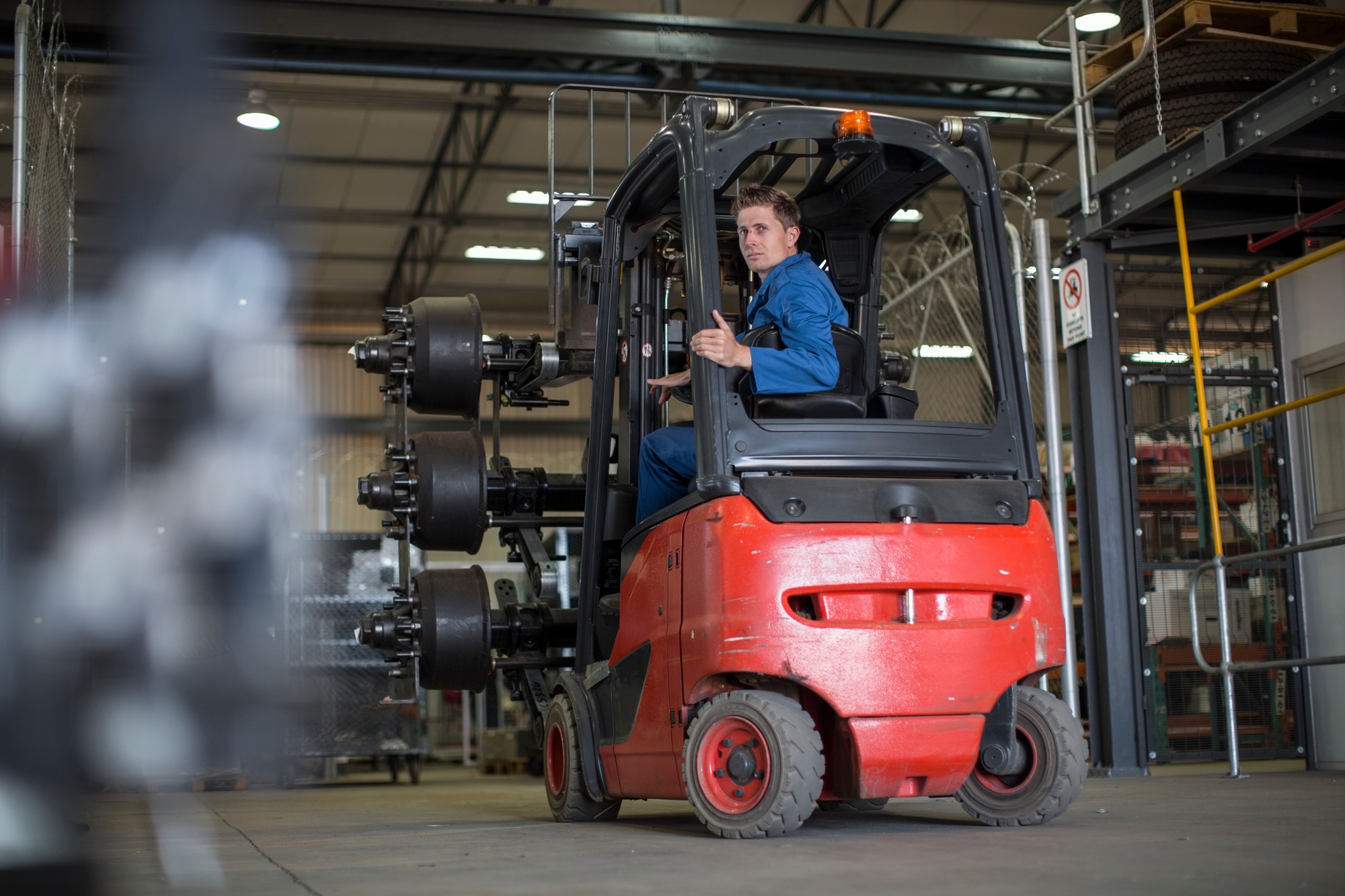 Factory working driving a fork lift in warehouse