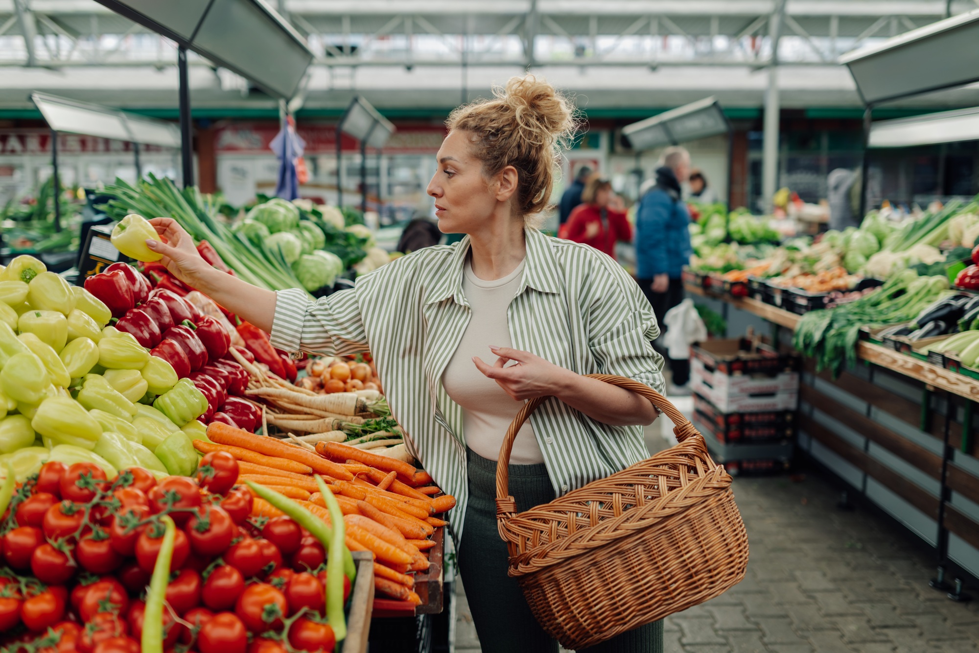 Female customer buying bell peppers at farmers market.