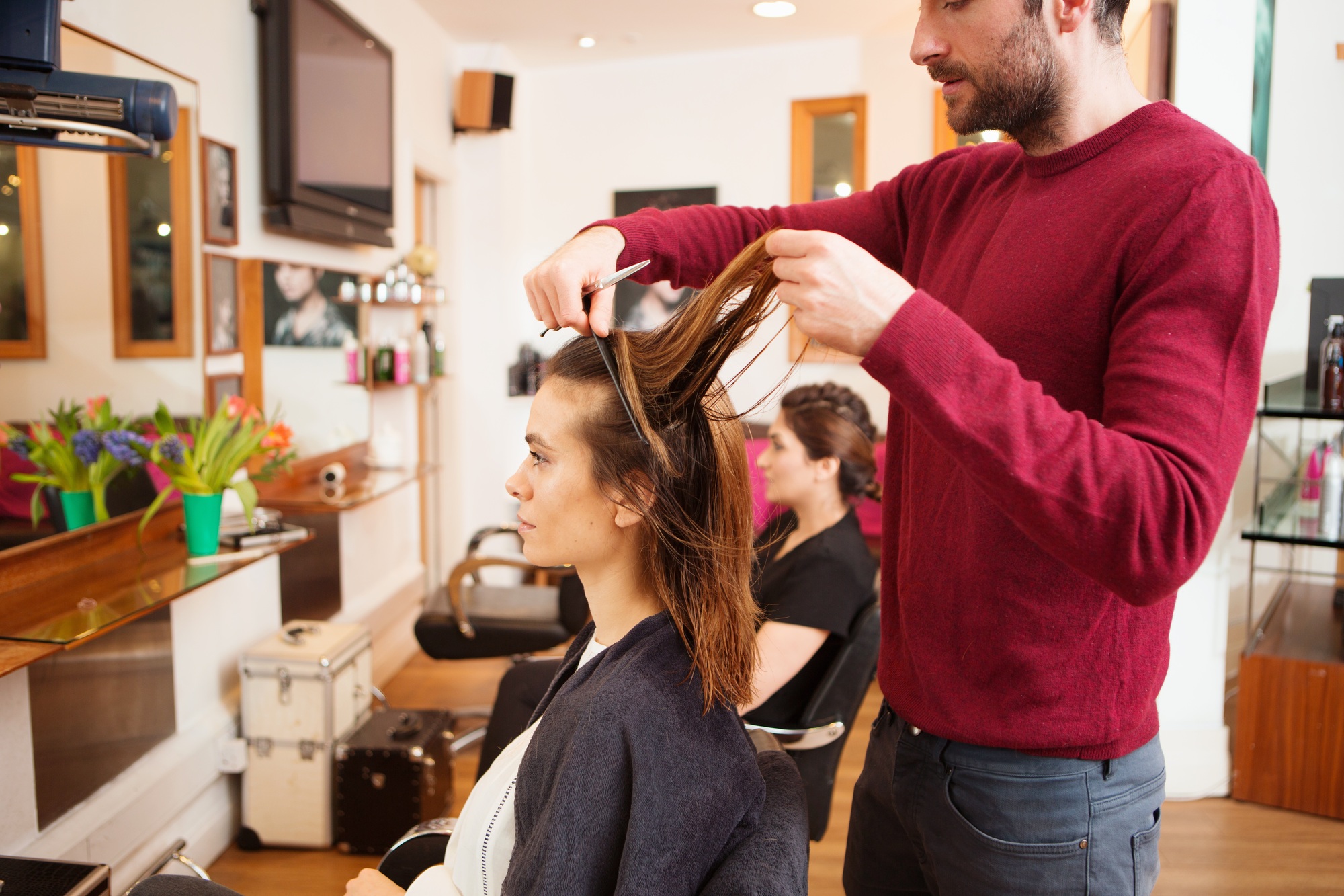 Female customer having long brown hair trimmed in hair salon