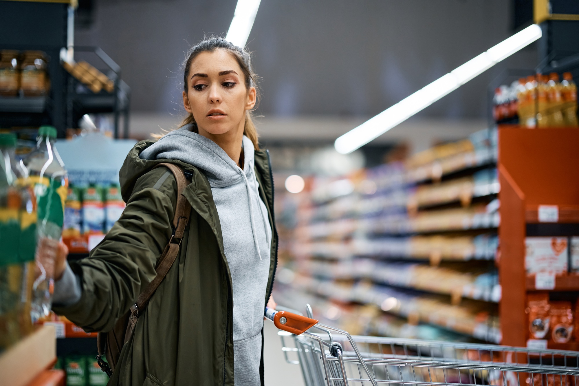 Female customer with shopping cart buying in supermarket.