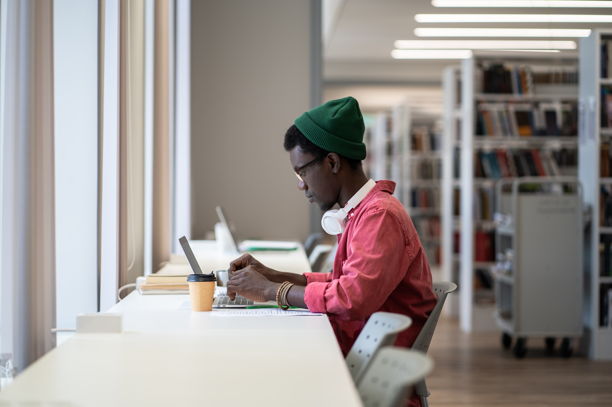 Focused African American student guy sitting at desk with laptop using online library database