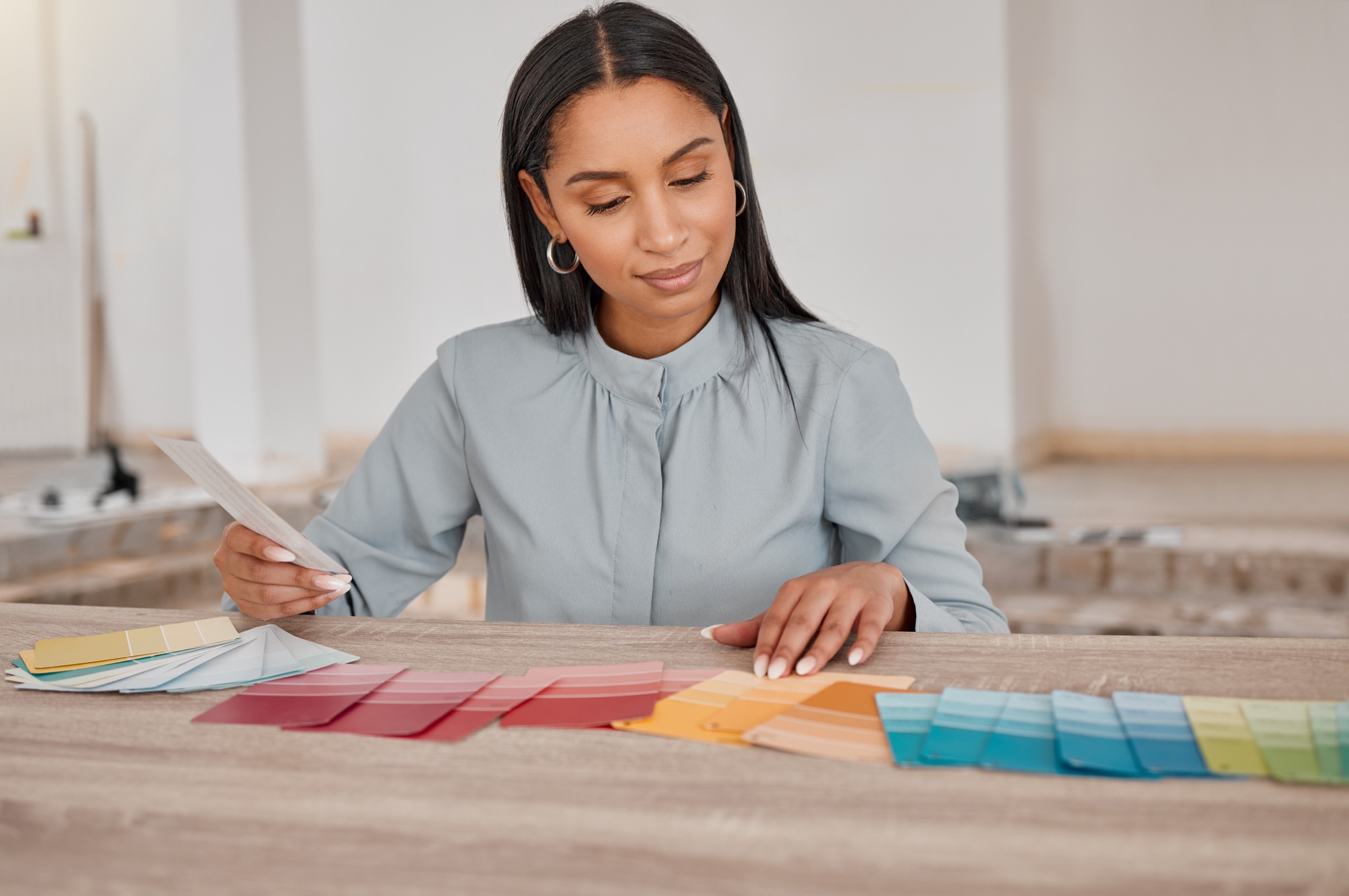 Shot of a young woman looking at different colour swatches while renovating her house