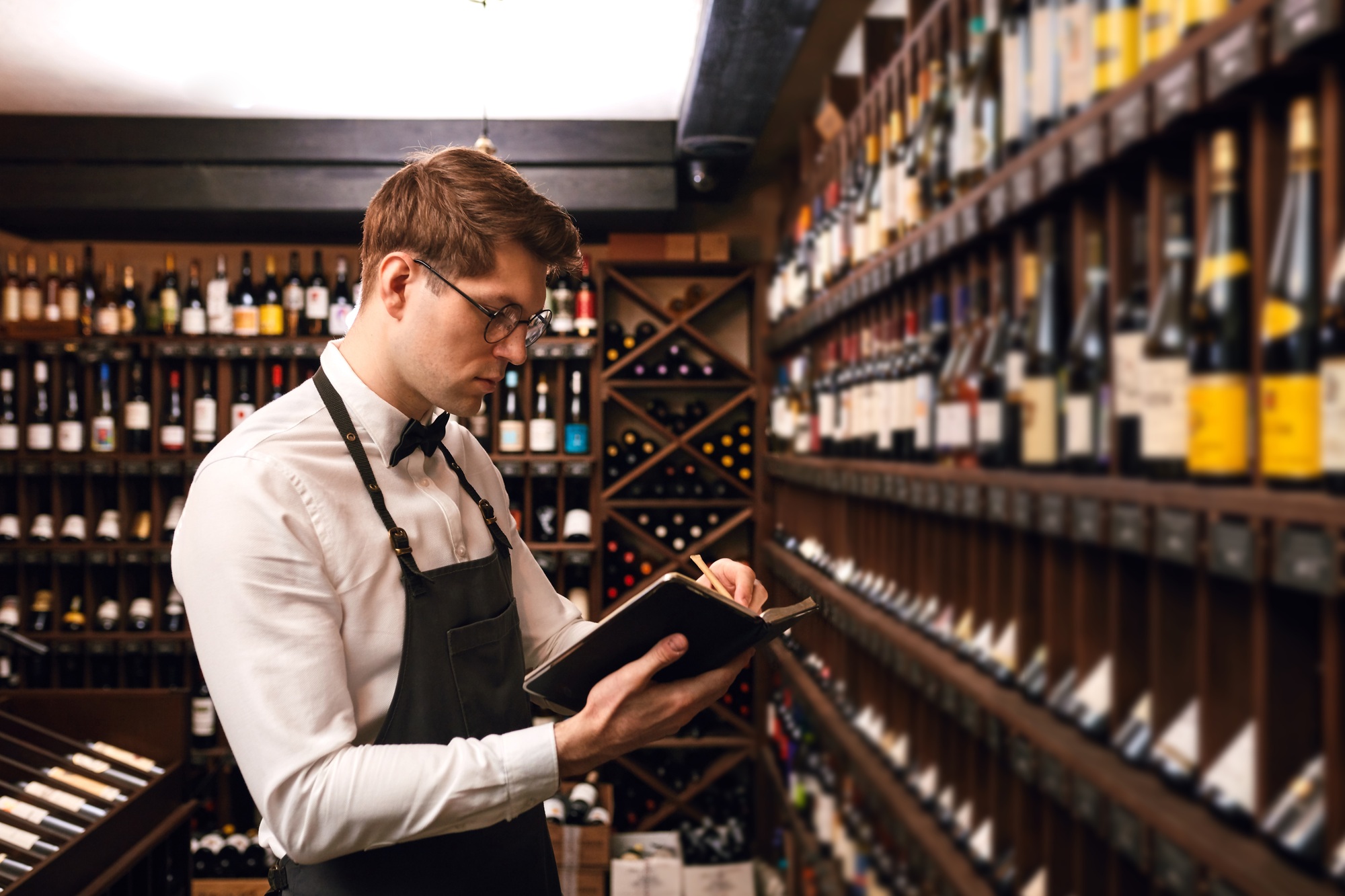 Sommelier putting down information of wine products in wine store