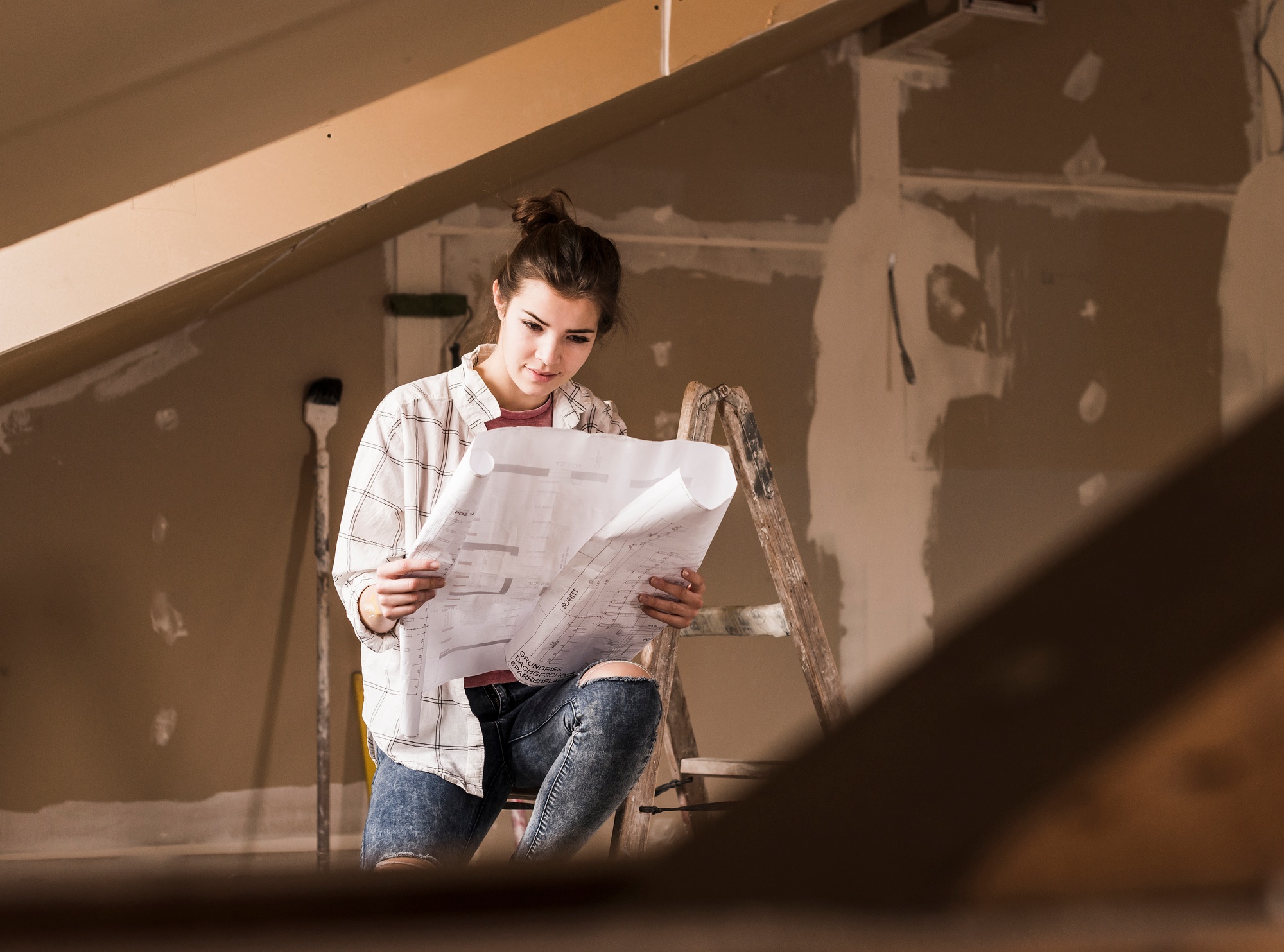 Young woman renovating her new home, holding construction plan