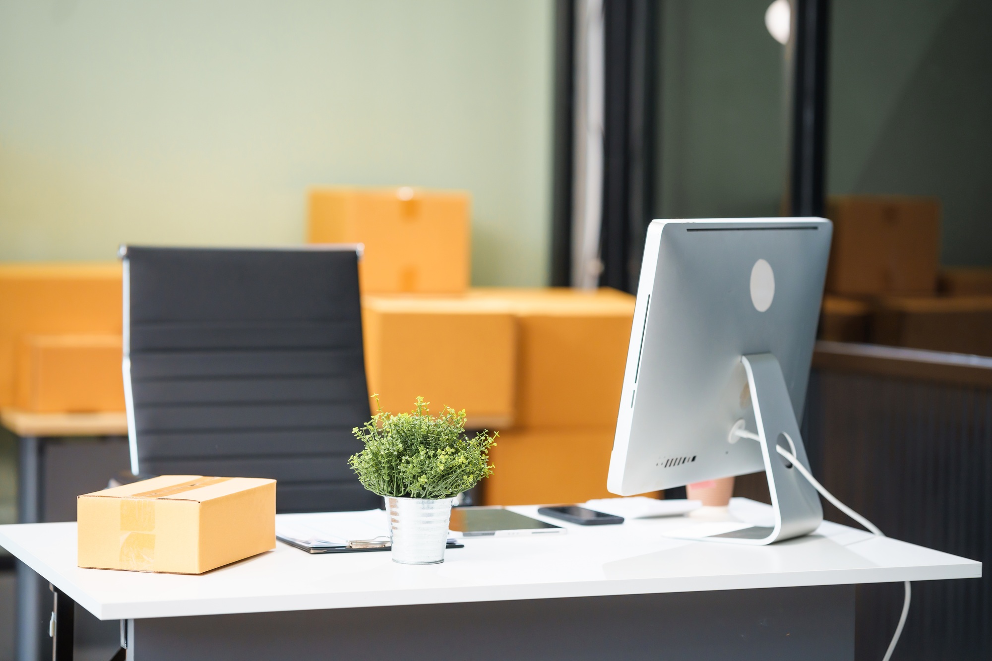 A work desk with a computer is show parcel box ready for shipment. setup reflects online business