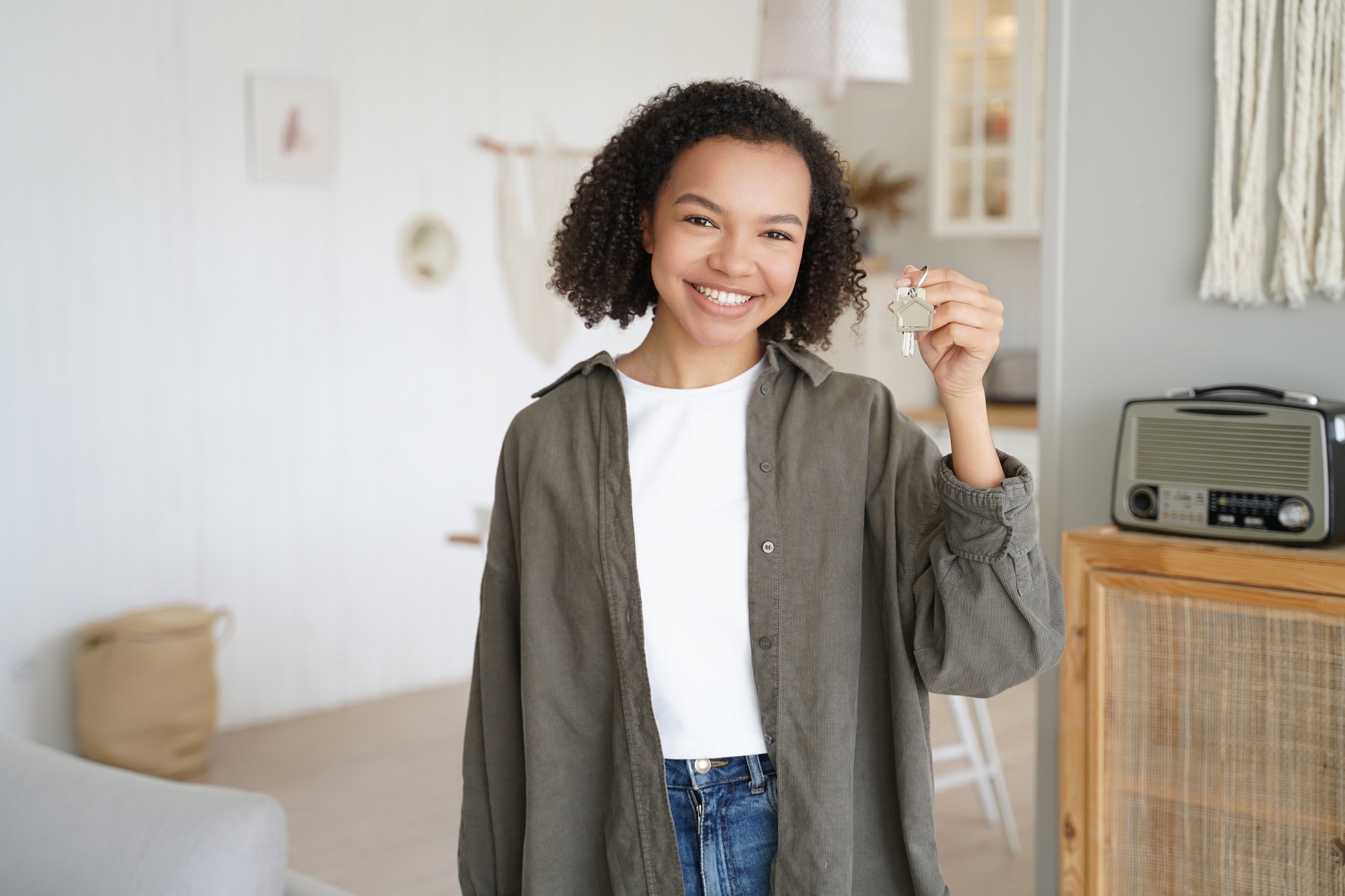 African american young girl showing keys of new house. Real estate service advertising, relocation