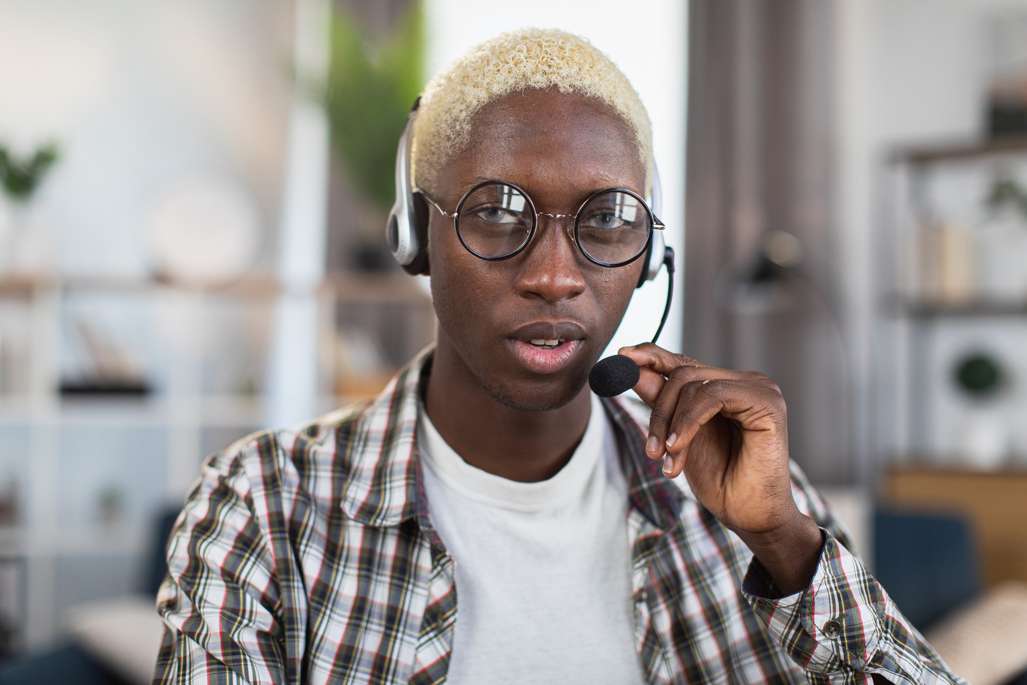 African man in eyewear and headset posting at home