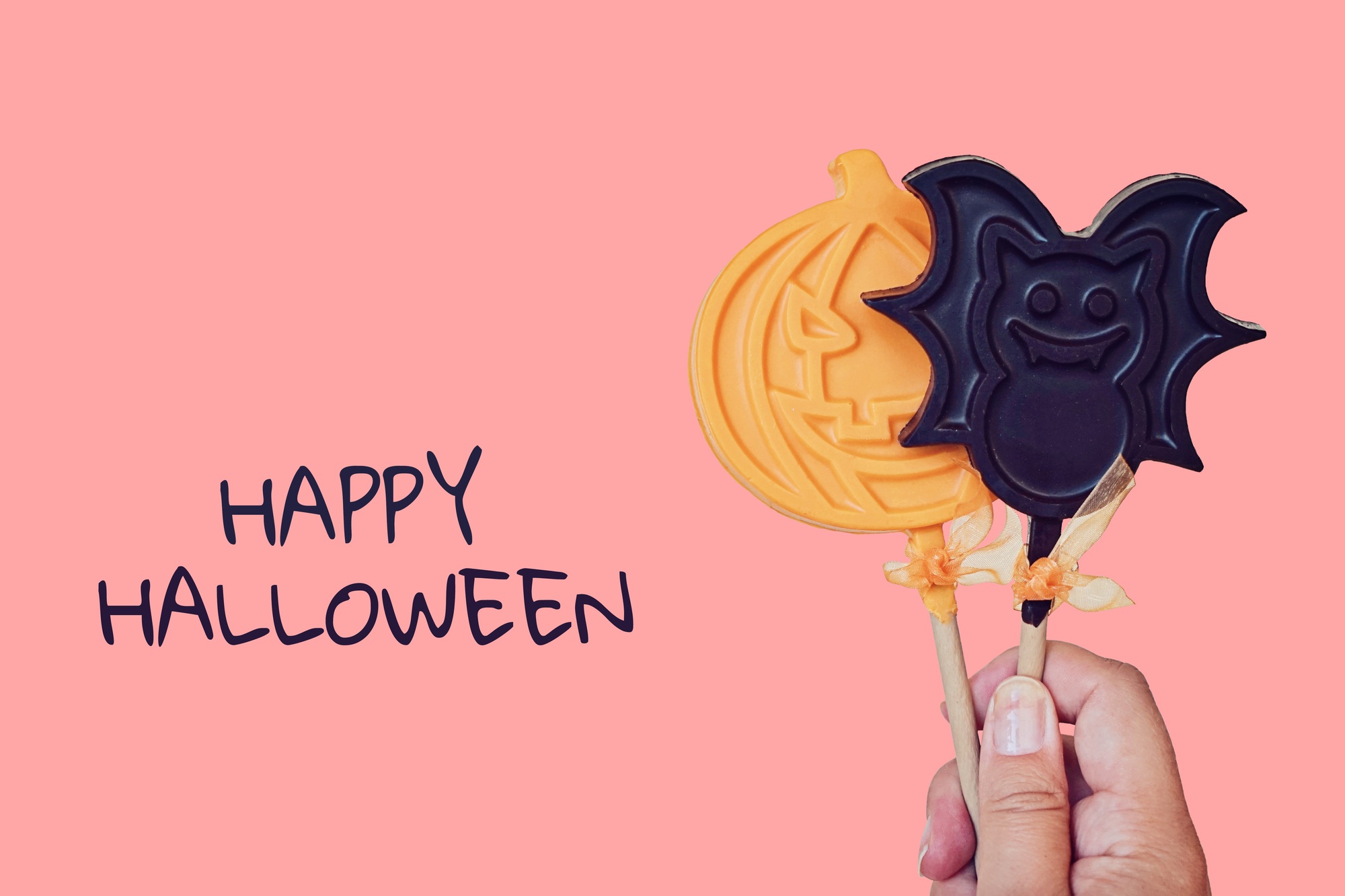 Chocolate lollipops in shape of pumpkin and bat. Pink pastel Halloween concept greeting card