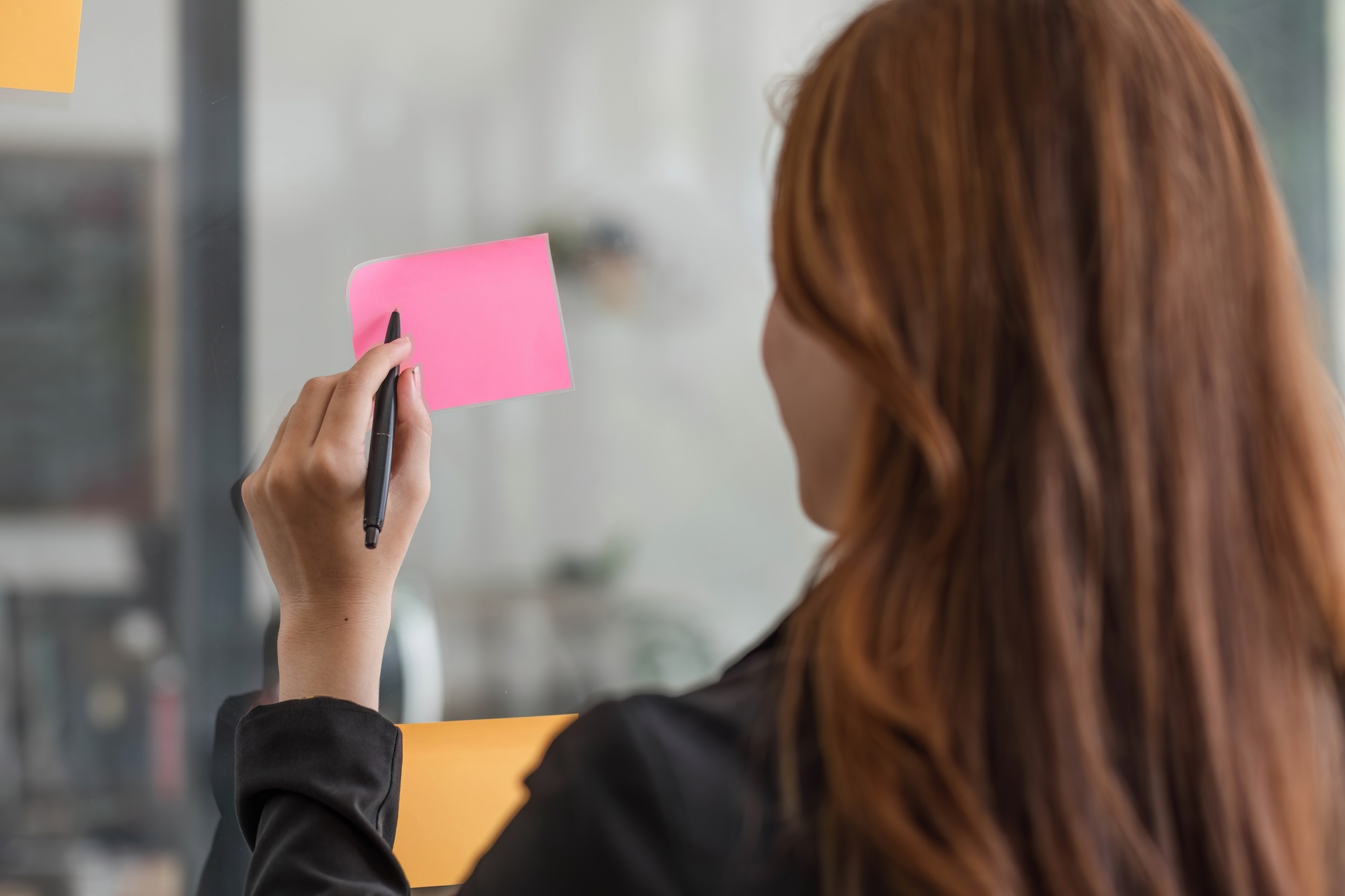 Close-up image of a beautiful young Asian female marketing assistant looking at the sticky note on a