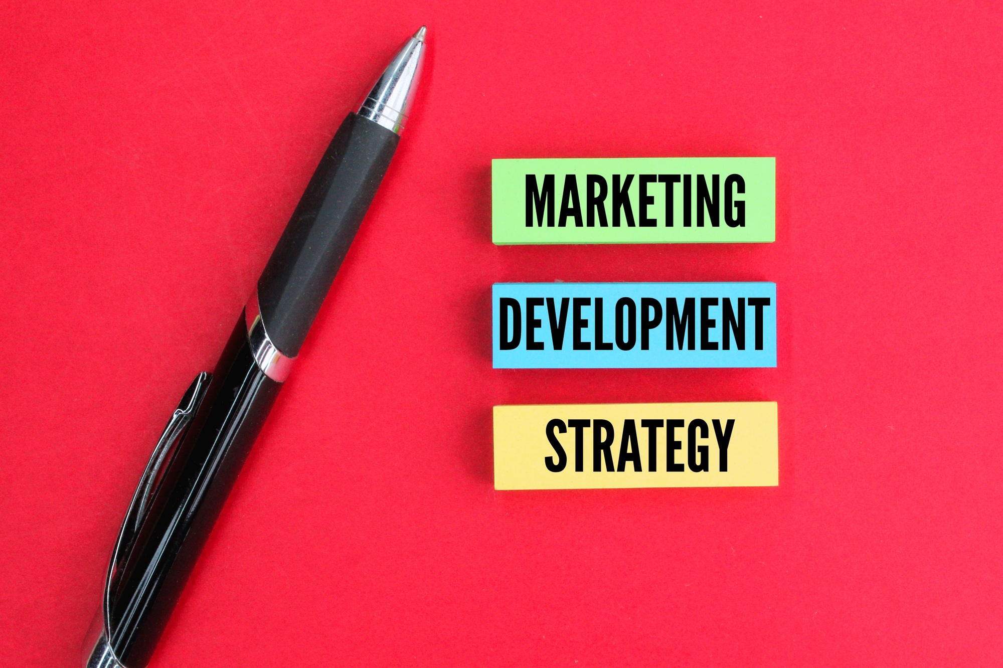 colored pen and paper with the words marketing, development and strategy.