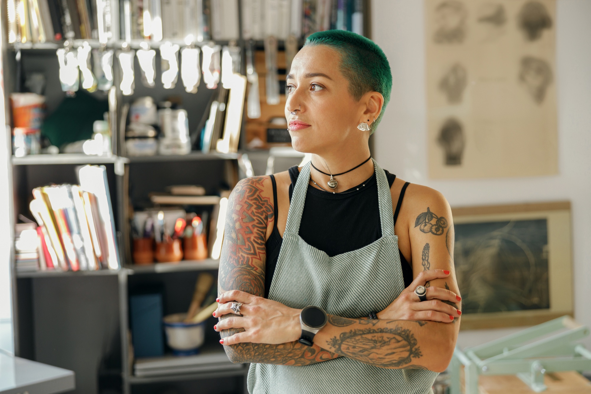 Creative female worker standing with crossed hands on background of design studio