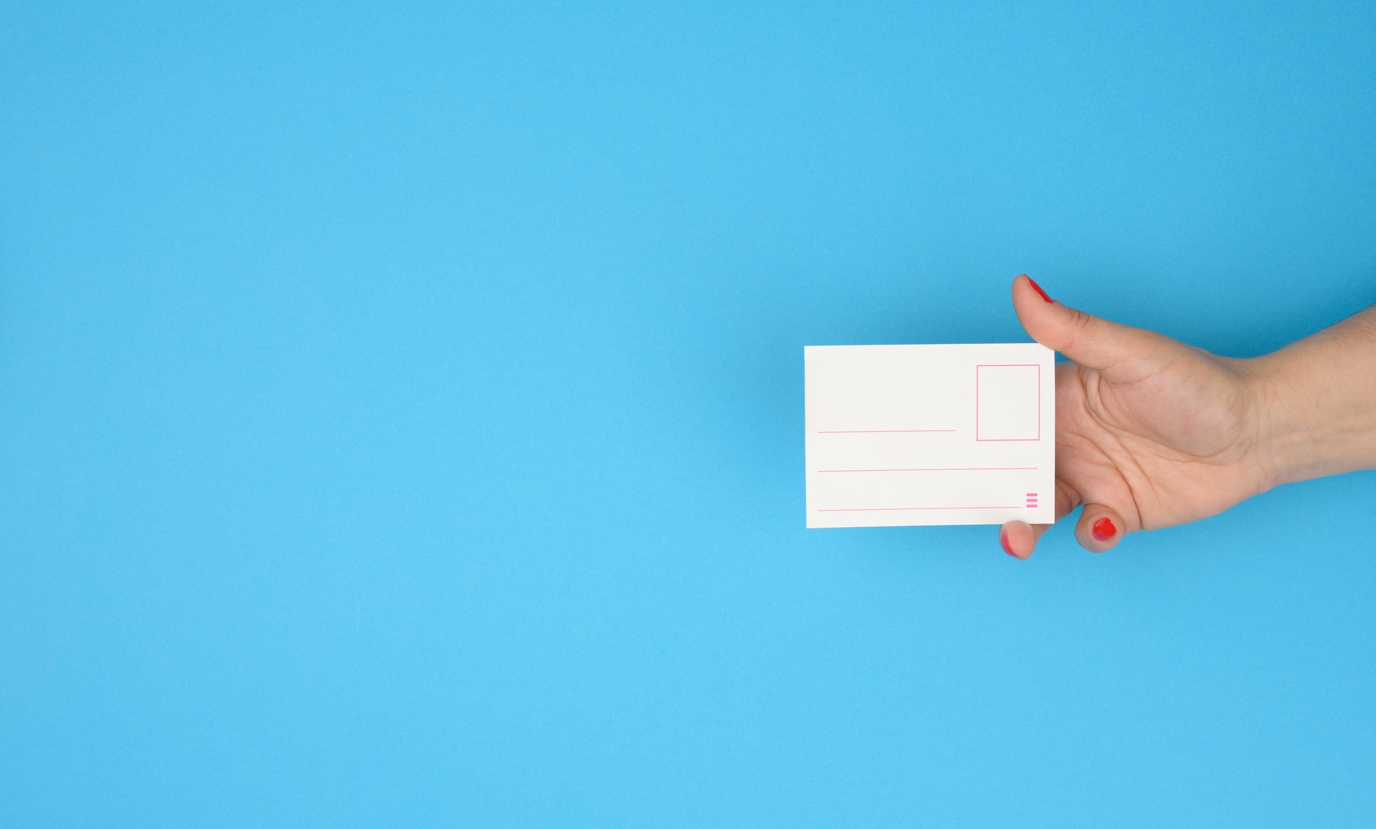 Female hand holding paper blank badge insert on blue background