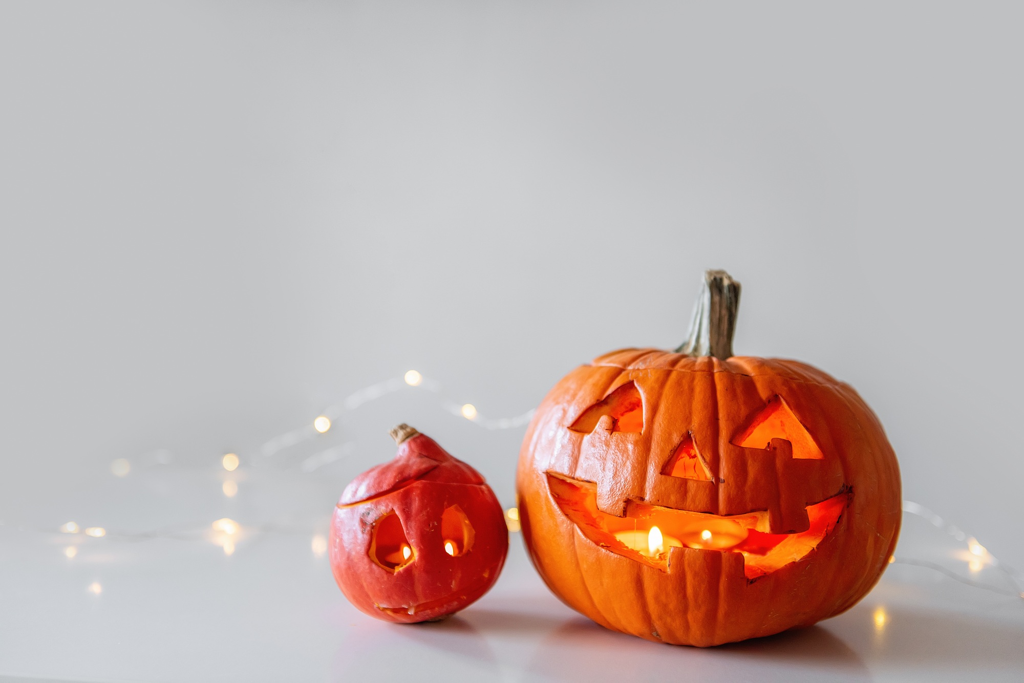 Greeting card in ginger and black tones for Halloween. Orange pumpkins lie on a white table