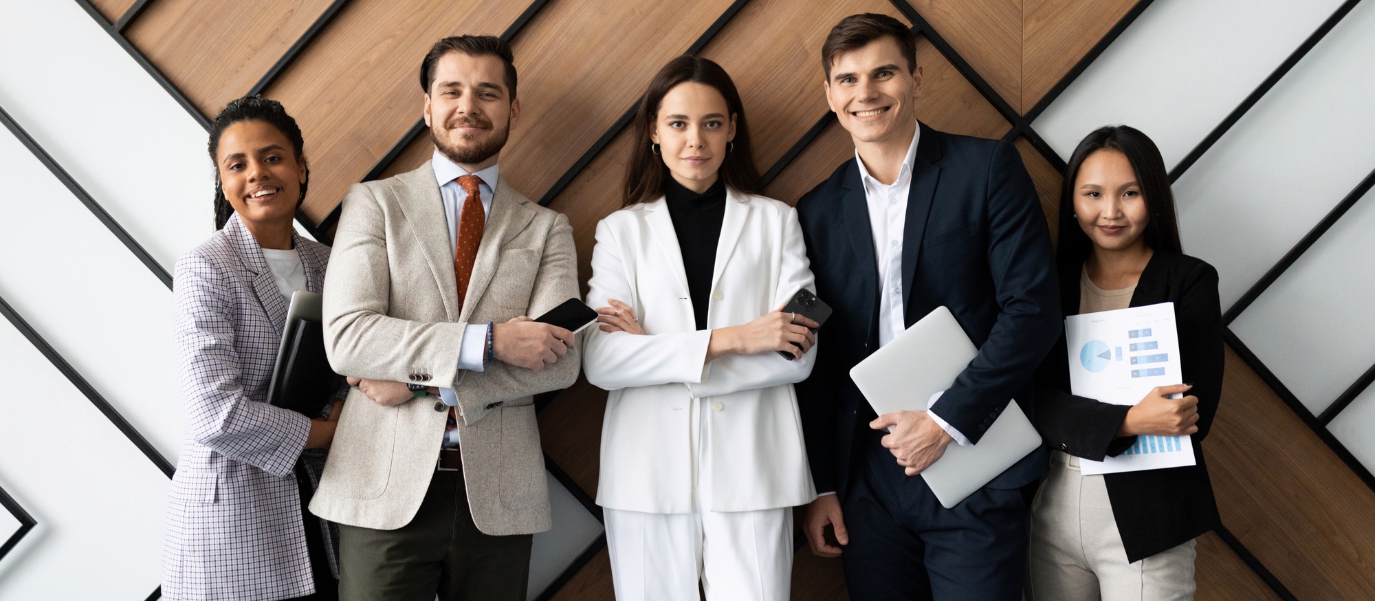 heterosexual multi national office staff with a smile looking at the camera standing against the