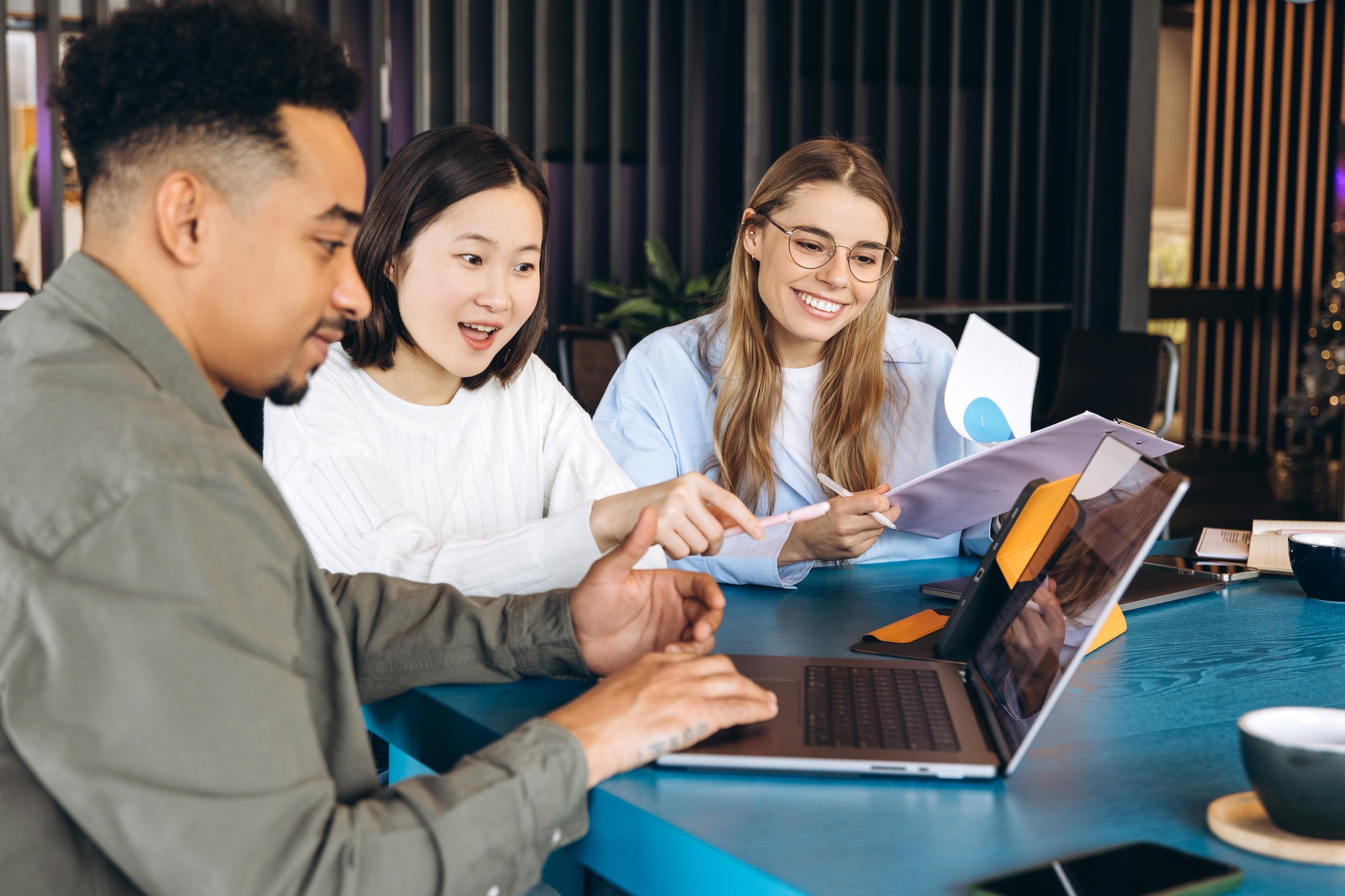 Marketing team analyzing data on laptop and documents in office meeting