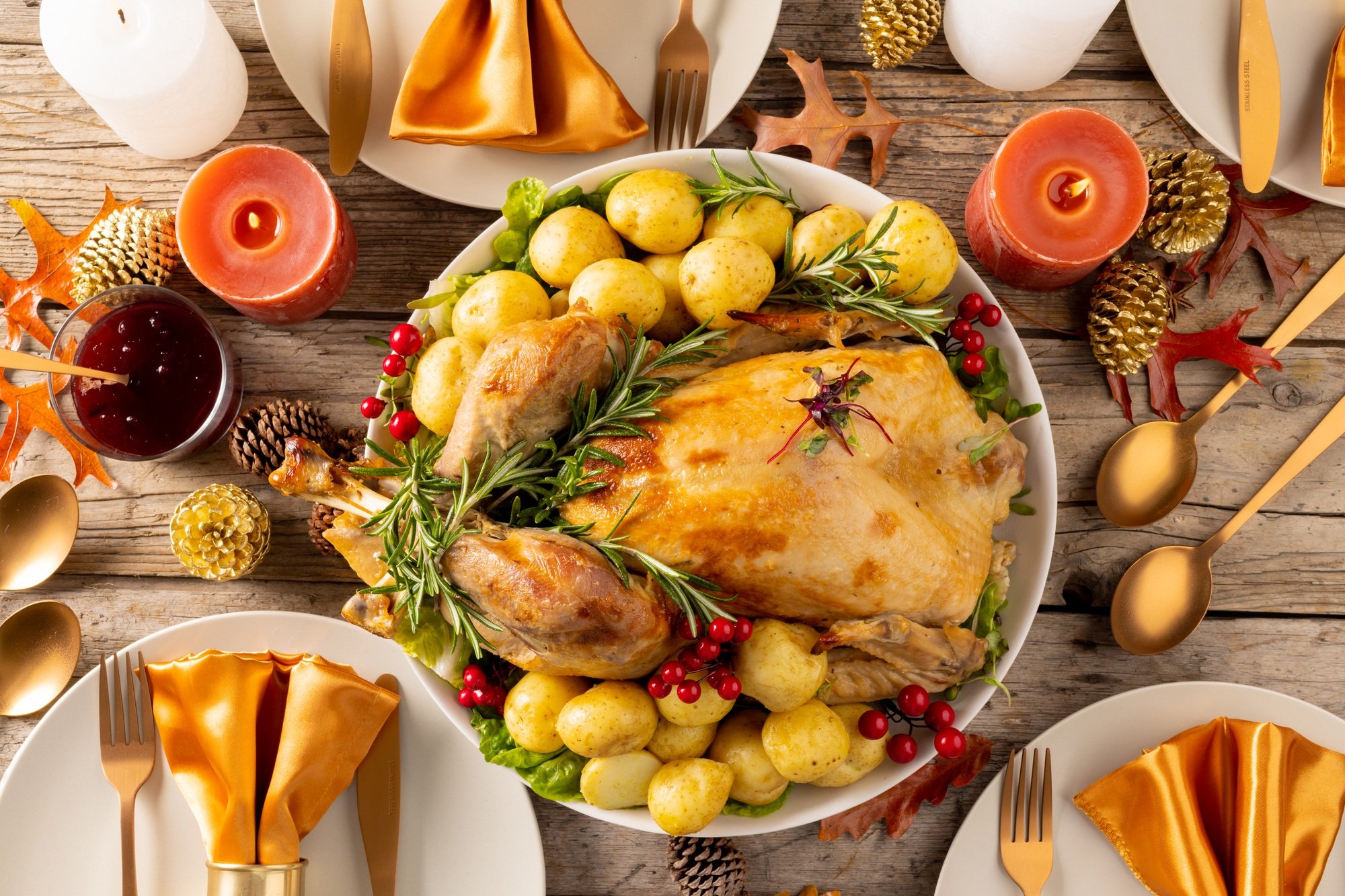 Overhead view of thanksgiving table with roast turkey, vegetables, candles and autumn decoration