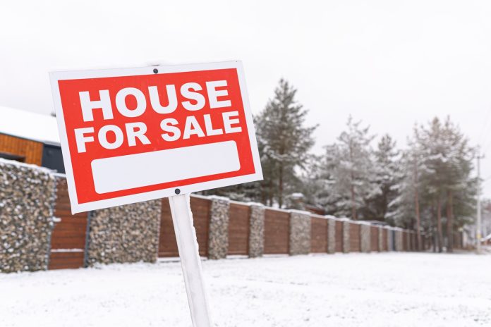 Red sign - house for sale, outdoors in winter. Buying suburban real estate