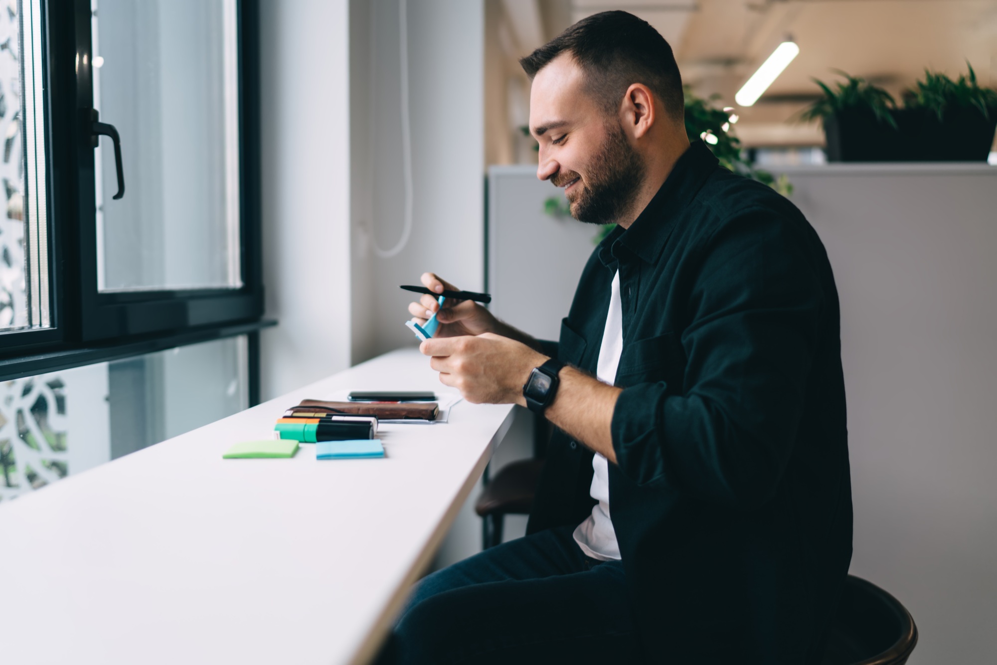 Smiling male influencer peeling off blue sticky note